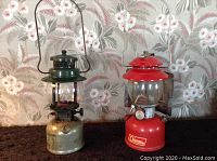 Two antique Coleman lanterns side by side, one red and one green, showing overall size and condition