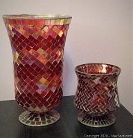 Tall red mosaic glass vase with flared opening and footed base, paired with a shorter red mosaic glass candle holder with curved sides and matching base.