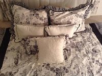 Close-up images showing black and white toile comforter, bed skirt and decorative pillows with ruffled edges and lace accents.