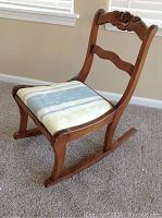 Side view of the rocking chair showing its curved maple finish wood frame and striped cushioned seat.