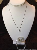 Full display showing necklace with blue stone pendant, bracelet, and earrings on a jewelry stand
