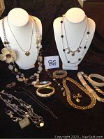 Full display of assorted ladies jewelry including necklaces, bracelets, rings, earrings, and pins on black cloth background with two white bust forms