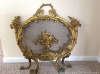 Front view of entire brass fireplace screen showing decorative frame and mesh