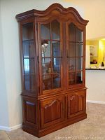 Front view of china cabinet showing arched bonnet top, glass doors and wood base