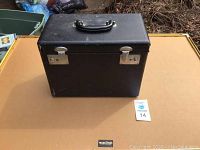 Front view of closed black carrying case with metal latches and handle