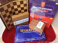 Group photo of the games showing packaging and game boards, including Chess wooden board, Sequence blue box, Balderdash purple/red box, Bombay box, and a small wooden X and O set.
