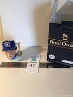 Front side view of the Royal Doulton Toronto Blue Jays ceramic bust with ruler and lot tag visible, showing detailed face and cap logo.