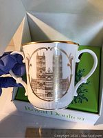 Photo of the mug showing detailed gold architectural design of Westminster and white porcelain with gold rim and dual handles.