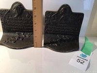 Pair of brass bookends with Native American female profile, floral decoration, and poetic text visible on the front.