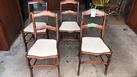 Four wooden dining chairs grouped together in garage