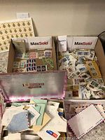 Four boxes filled with stamps in sheets, loose used stamps on cut envelope pieces, and some envelopes.