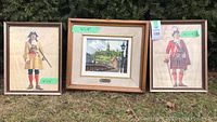 Three framed art prints displayed outdoors showing varying sizes and slight water damage to frames.