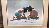 Frontal view of framed painting showing two girls playing in sand and seagulls overhead