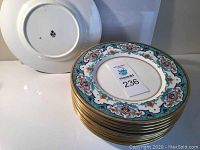 Stack of 11 Mintons plates showing detailed floral pattern and gold rim