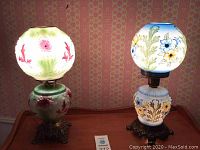 Two Gone With The Wind lamps together on wooden table, showing size and glowing details.