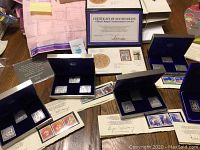Overview of five presentation boxes, first day covers, certificates and papers laid out on table