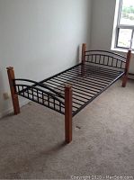 Side view of a single metal and wood bed frame showing metal slats and wooden posts at corners.