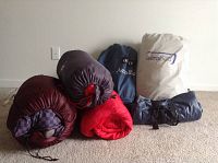 Photo of three rolled twin sleeping bags and three packed mattresses including two AeroBed air mattresses in bags and one rolled self-inflating mattress