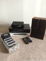 Overview of all audio components: power transformer amplifier, two remotes, stacked AVT box, Rotel CD player, AMC tuner, and four Realistic speakers.