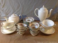 Full lot overview showing white cups, saucers, two pots, patterned cups and saucers