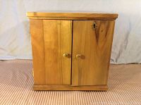 Closed wooden coin storage box with dual front doors and brass knobs.