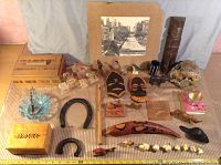 Full view of assorted ornaments, wood boxes, glass dish, horseshoes and other small items arranged on fabric.