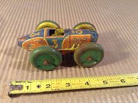 Side view of the vintage tin friction toy car showing the paint design and number 3, placed beside a tape measure for size reference.