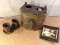 Front view of vintage magic lantern projector with two detachable lenses and framed photo placed beside it