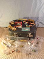 Lot of fishing lures arranged on and around gray carrying case showing the variety of lure types and packaging.