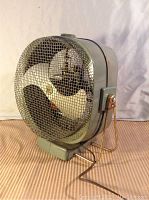 Front angled view showing the metal blades, mesh, overall fan shape, and stand.