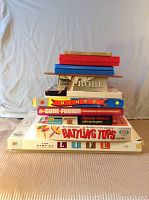 Stack of 11 boxed board games including The Game of Life, Bingo, Cube Fusion, Probe, Battling Tops, and others, showing titles and box conditions.