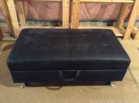 Closed black leather storage ottoman foot rest with tufted top and metal legs