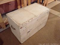 White wooden storage trunk closed, showing exterior and side handle.