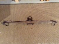 Full view of the wooden whippletree showing iron rings at both ends and center hook mechanism.