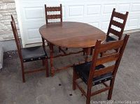 Full view of antique oval gate leg table with four matching oak chairs