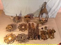 Full lot overview showing 11 antique lamp parts including bases, metal plates and sconce parts, spread on a beige fabric background.