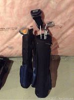 Two golf bags standing side by side, each holding multiple junior golf clubs with visible driver, irons, and putter heads
