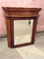 Front view showing the framed mirror door with decorative molding and crown top.