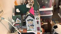 Ceramic Victorian Village church building with tall green spire, snow accents, and Christmas decorations, showing front and side view details