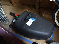 Black hard plastic carrying case with handle, closed, with small bottle of fluid visible beside it