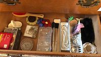 Drawer showing assorted jewelry including pearl necklaces, earrings, brooches, and small charm accessories.