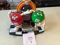 Front view of colorful M and M Juke Box Dispenser with red and green M and M characters and black and white checkerboard base