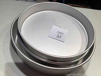 Top view of three stacked round metal cake pans showing smooth interior surfaces and edges.