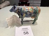 Photo of the full cow figurine showing the abstract art design and attached informational tag