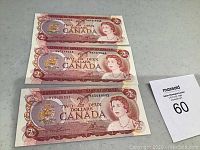 Front side of three 1974 Canadian $2 bills, showing Queen Elizabeth II portrait and denomination details.