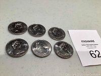 Six Canadian dollar coins dated 1986 laid out on a table with visible Queen Elizabeth II profiles on one side.