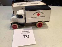 White and black die-cast model 1926 Mack delivery truck bank with red wheels, showing side decal for Elmira Maple Syrup Festival and 1991 5th anniversary toy show. New in box with original packaging box behind.