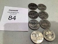 Eight Canadian dollar coins displayed on a flat surface next to a Maxsold lot number card.