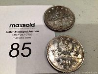 Photo showing both 1952 and 1961 Canadian silver dollar coins placed beside MaxSold auction card #85.