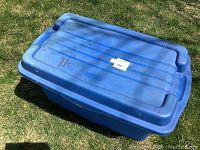 Photo of large blue hinged plastic storage bin from above on grass.